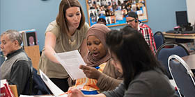 Teacher works with adult English language learners students in ESL classroom